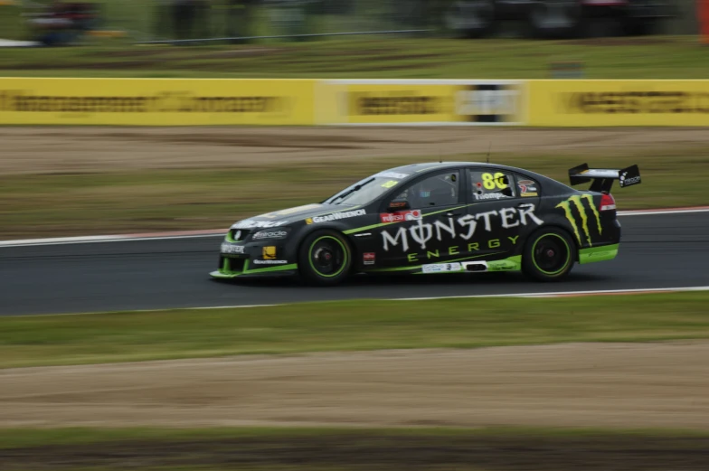 a green and black race car driving down the road