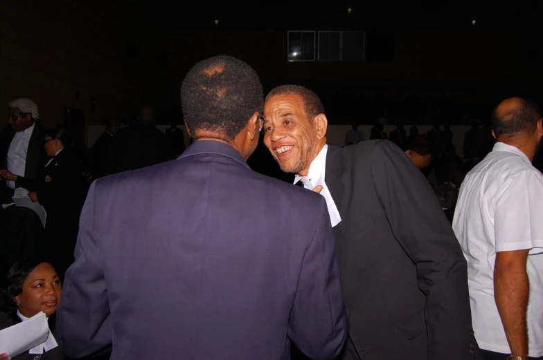 two men in purple suits talking on a cell phone