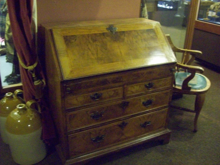 a wooden desk and chair next to a big mirror