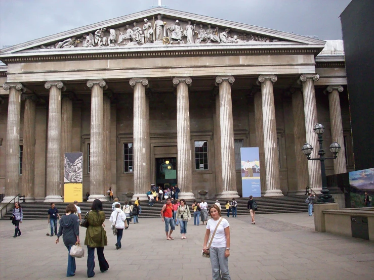 people walking around a museum with huge columns and artwork