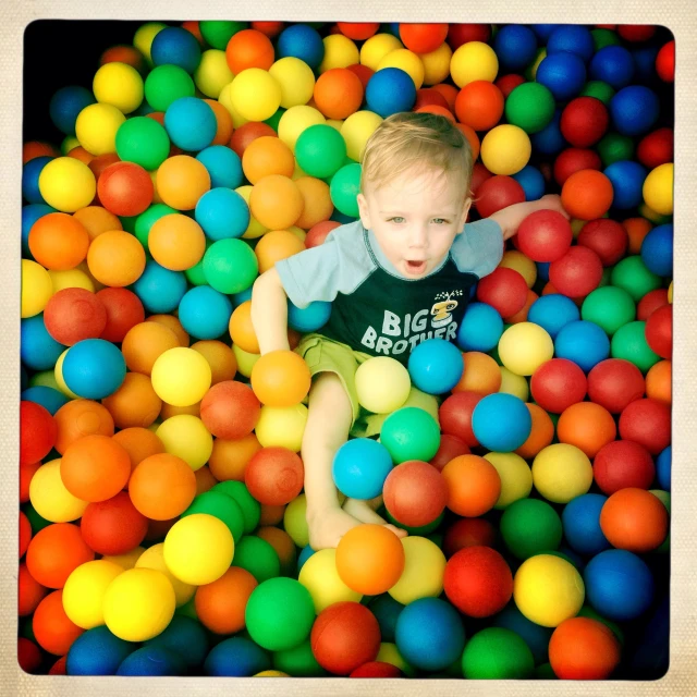 a child in a ball pit of plastic balls