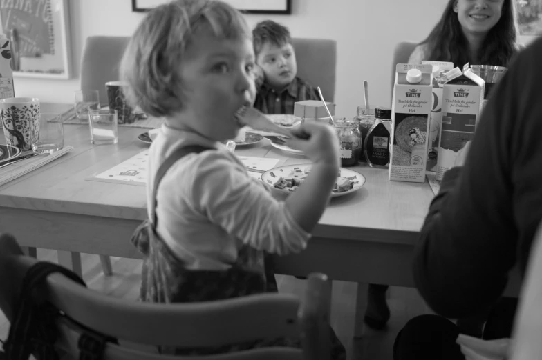 the children are sitting at a table eating