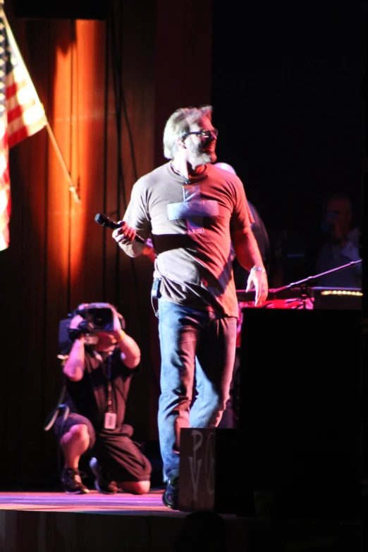 a person standing on stage singing with a microphone in front of him