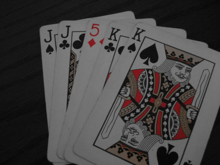 a three pair of cards in one playing card which is surrounded by four of spades and five of clubs