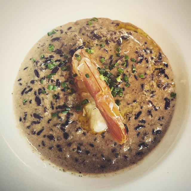 a shrimp on a bowl of cream soup with chives