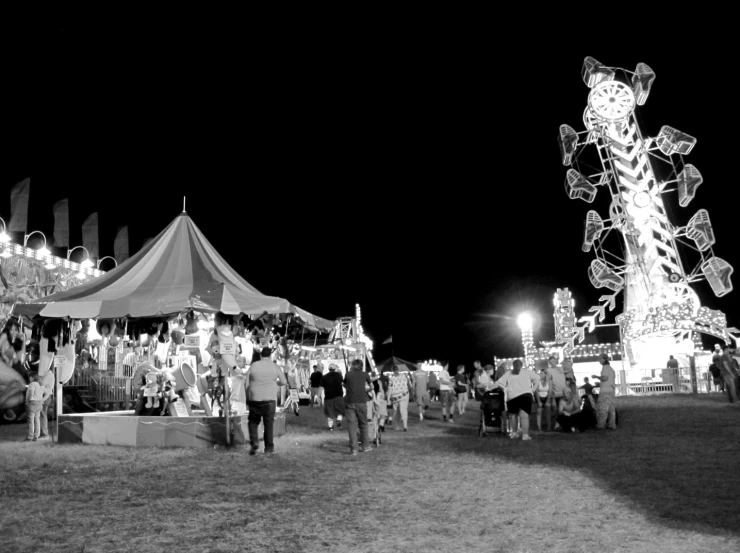 a group of people walking around a carnival with lights