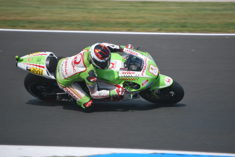 the person is racing a green motorcycle around the track