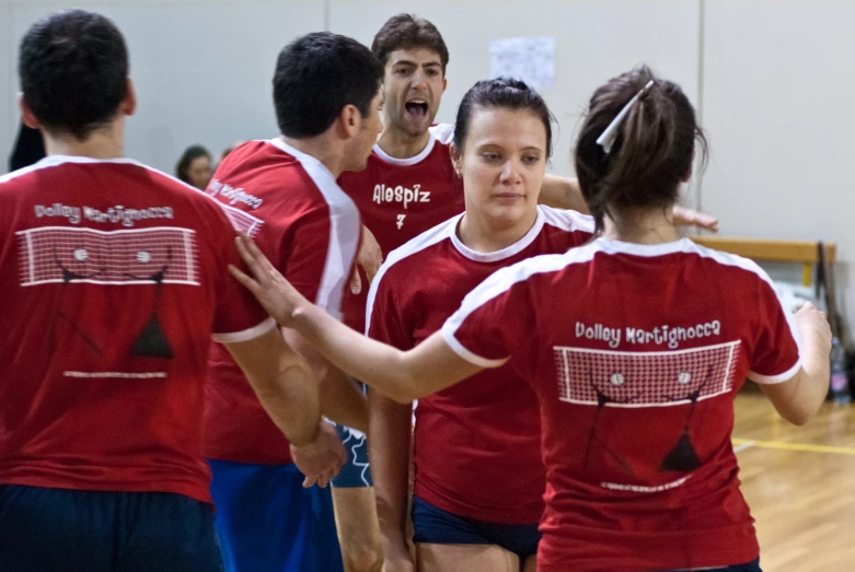 group of people with red shirt talking while standing on court