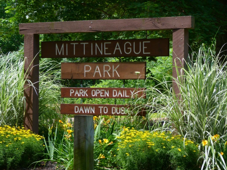 a sign with different directions in the middle of a park