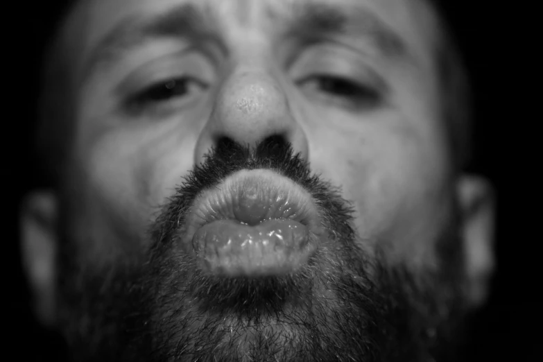 black and white pograph of bearded man's face making weird face