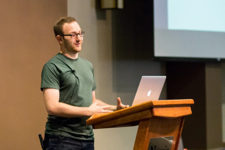 a man standing in front of a wooden podium talking