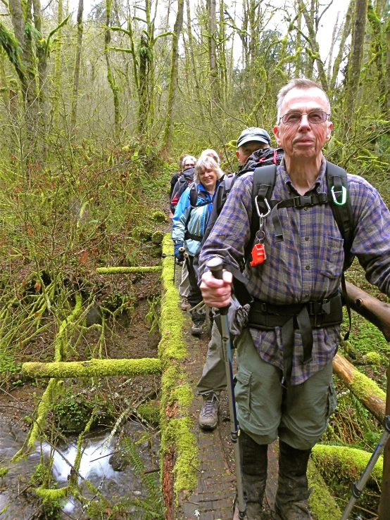 man with poles in a group hiking along a trail