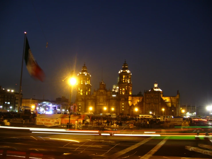 several buildings along a street at night, some are lit up