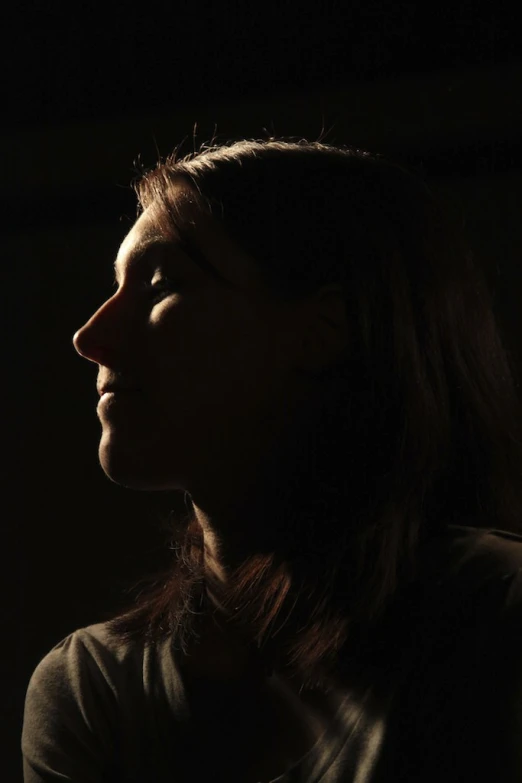 a woman's profile, lit by a spotlight
