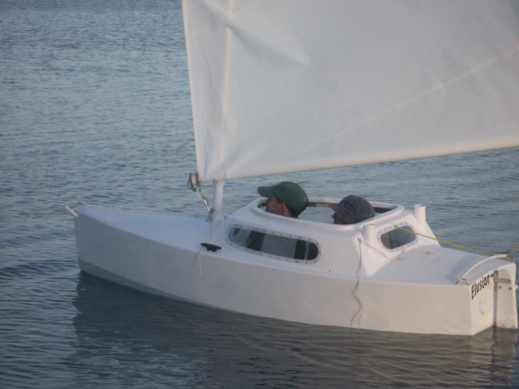 small white sailboat on water with man at helm