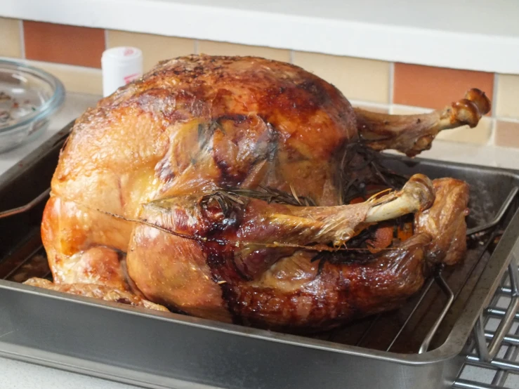 a roasted turkey on a roasting pan with gravy