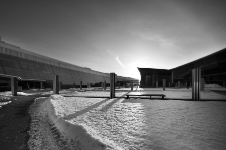 black and white pograph of a snowy park with a building in the background