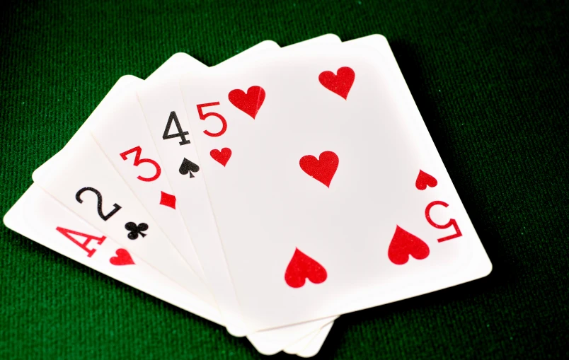 four playing cards are sitting on top of a green table