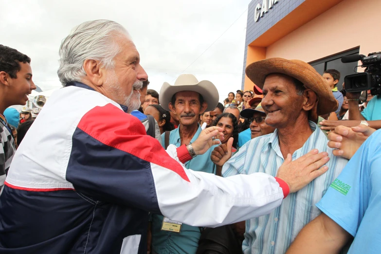 older man is smiling and greeting another older man on his phone