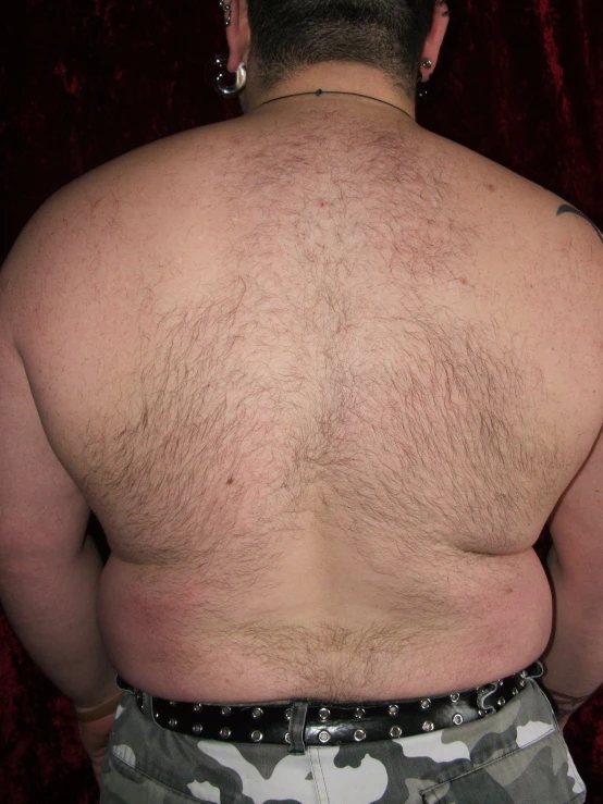 the back of an overweight man who has tattoos on his left chest