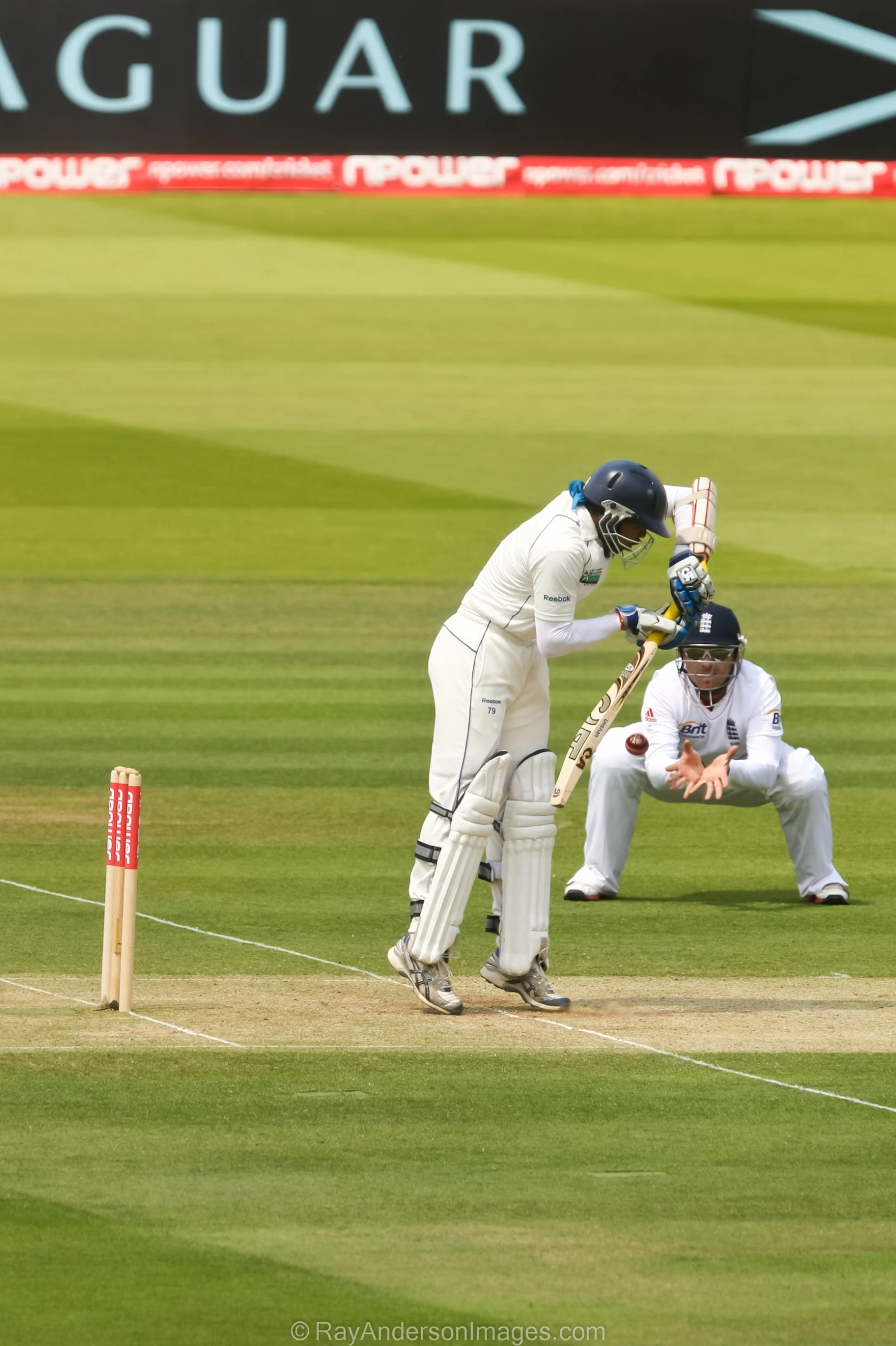 two men in white uniforms stand next to a ball