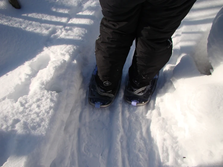 person in high rise snow boots on an open area of snow