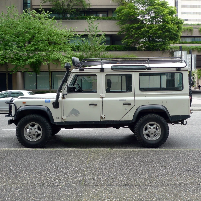 a white land rover driving down a street