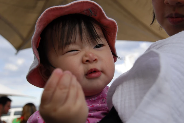 a baby girl wearing a pink hat next to an adult