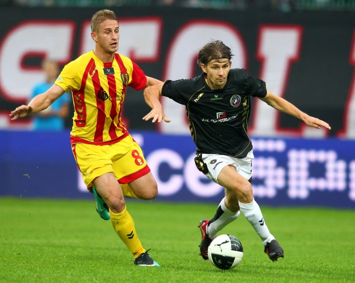 two young men play soccer on a field