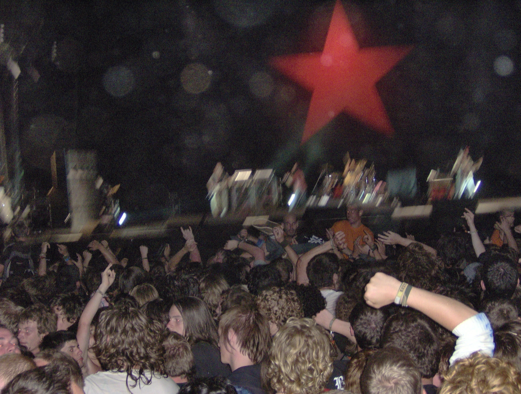 a crowd of people raising their hands up to a red star