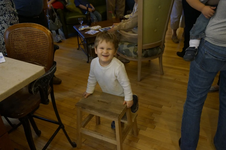 a little girl sitting on a wooden chair with her feet up