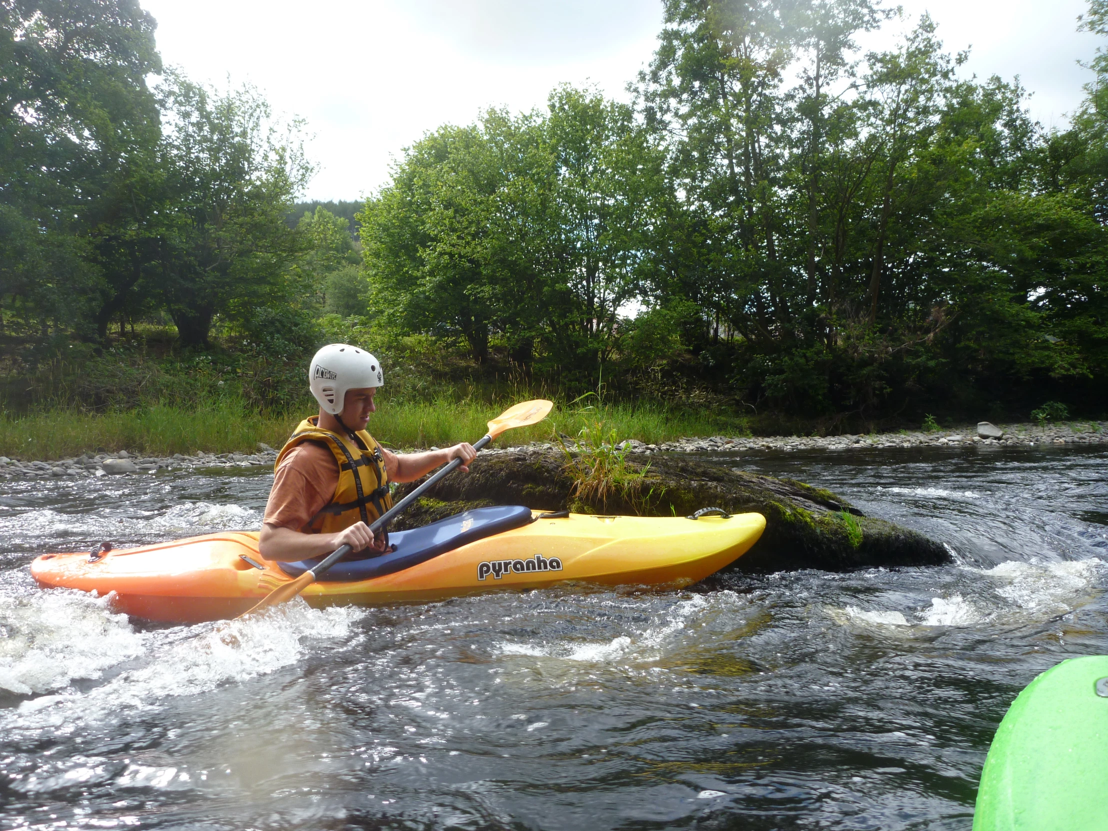 a man kayaking down a river in a yellow boat