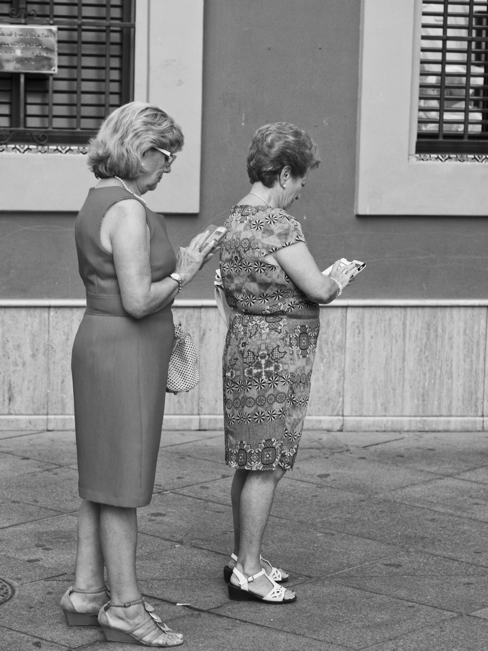 two women talking while standing on the side walk