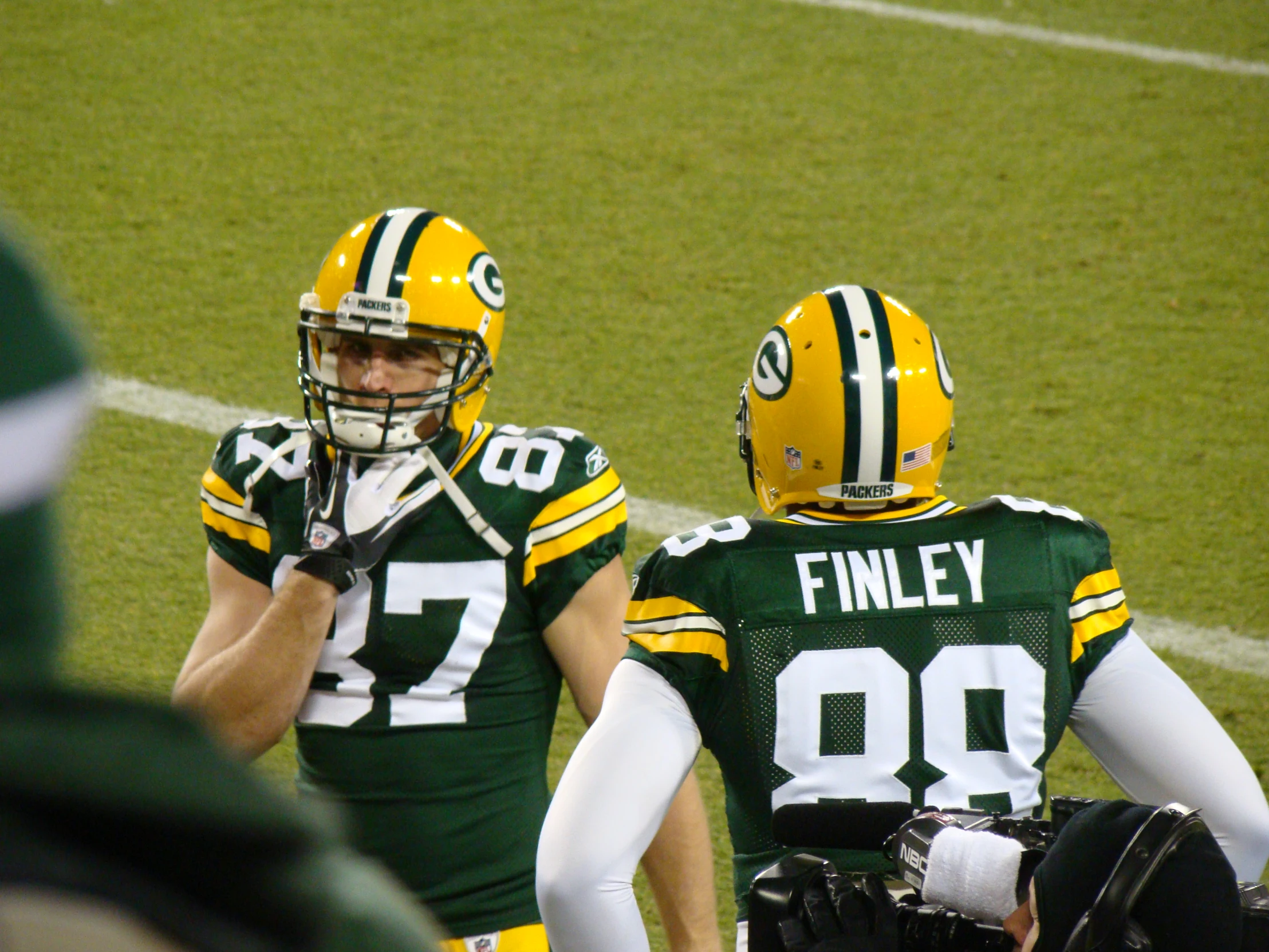 two football players in green and yellow uniforms are standing next to each other