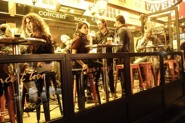 people sitting and standing around tables near a store