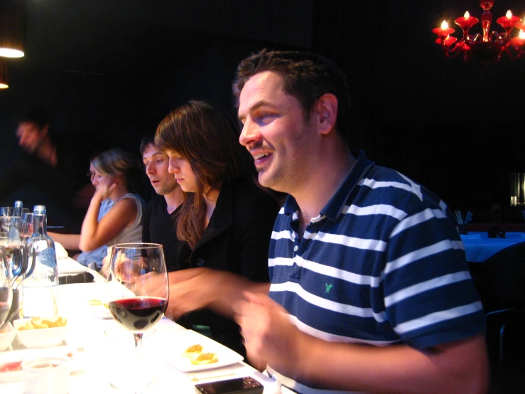 a man sits at a table with people and drinks