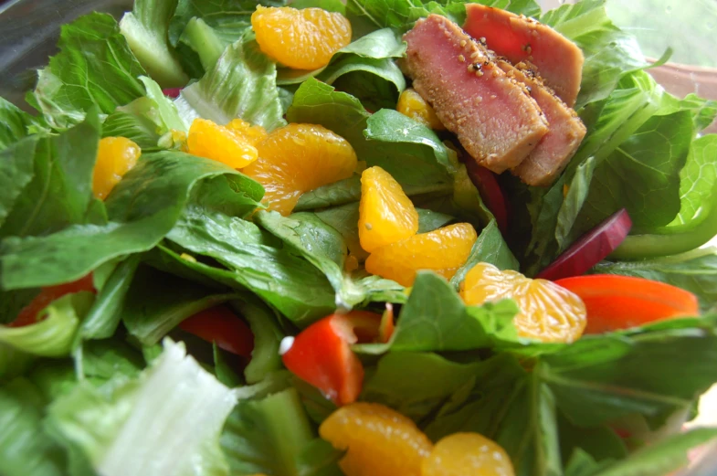 a salad with spinach, carrots, peppers and meat on top
