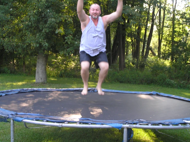 a man standing on a trampoline in a park