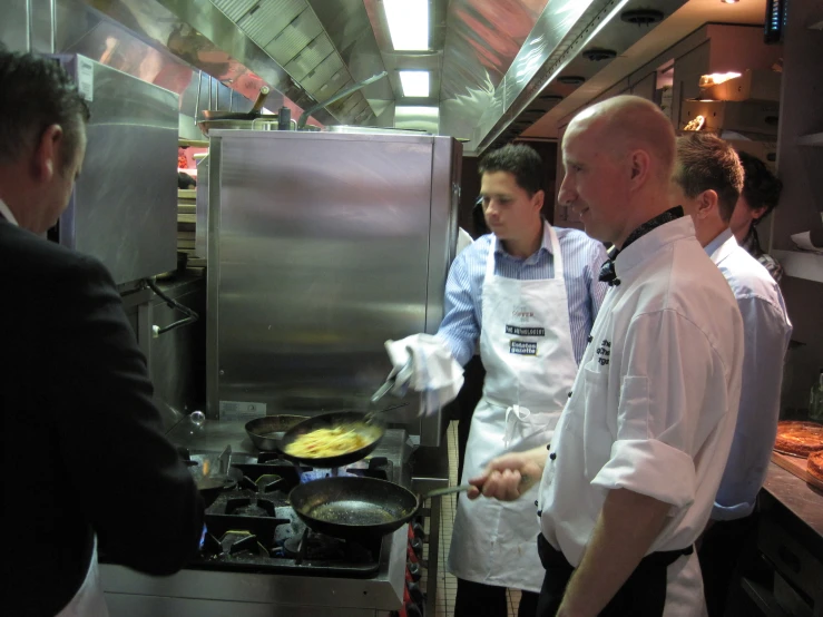 two men and one man cooking food in a restaurant