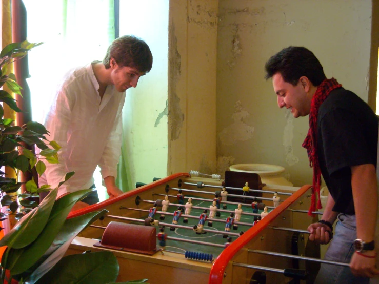 two men in a living room examining a table football game