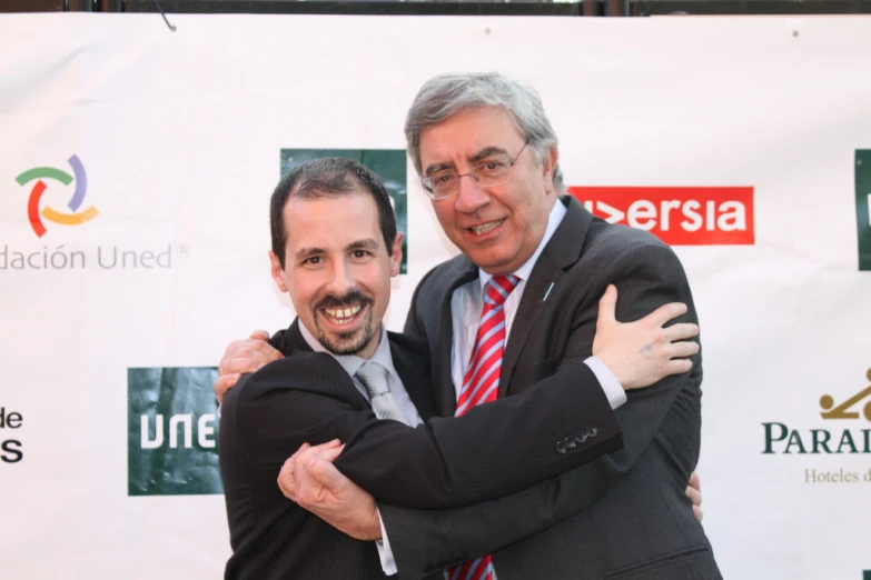 two men hug each other while standing on a stage