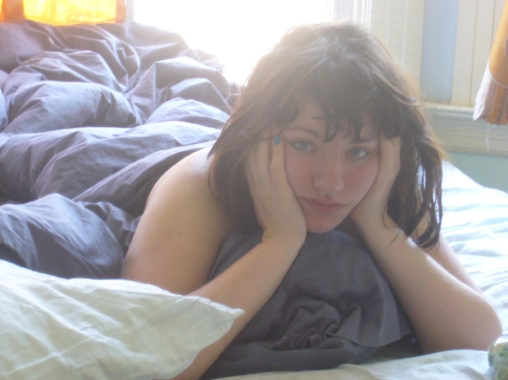 a young woman laying in a bed looking confused