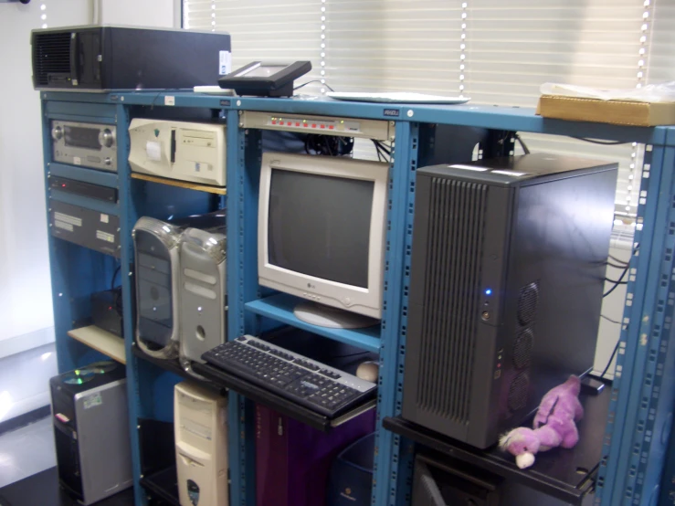 computers are stacked on top of shelves on a desk