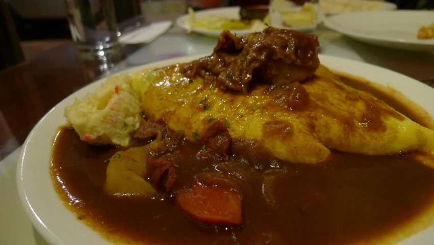 the white plate is holding a dish with meat and gravy