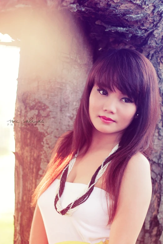 a young woman standing near a tree, posing for the camera