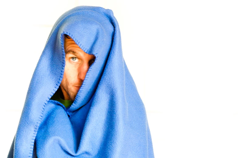 a man peeking out from under a blue blanket