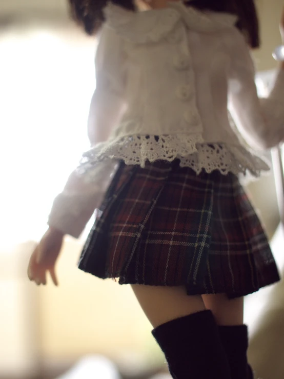 there is an adorable doll dressed in a plaid skirt and boots