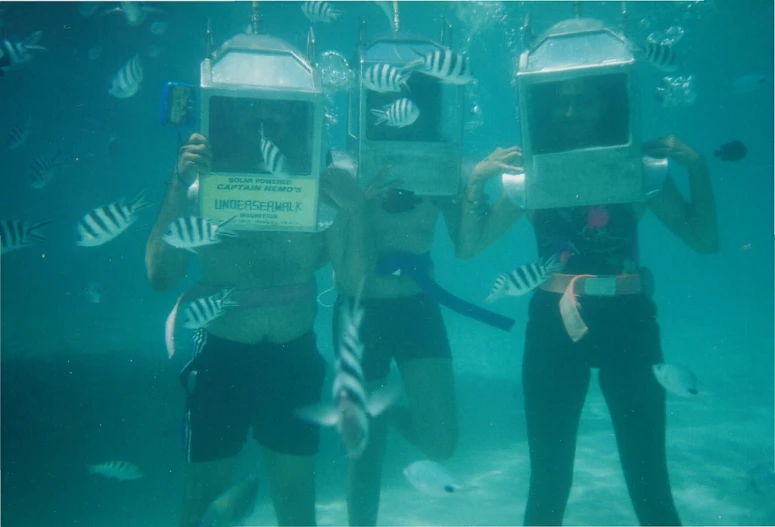 three people holding up framed pos and in the water