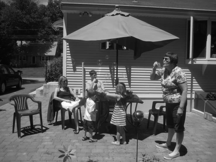 black and white po of four children sitting in chairs on a patio