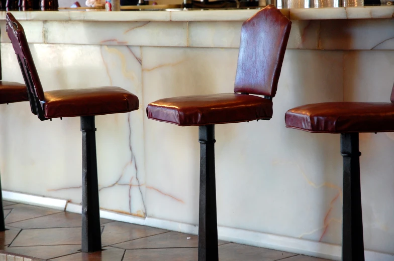 three leather stools in front of a marble wall